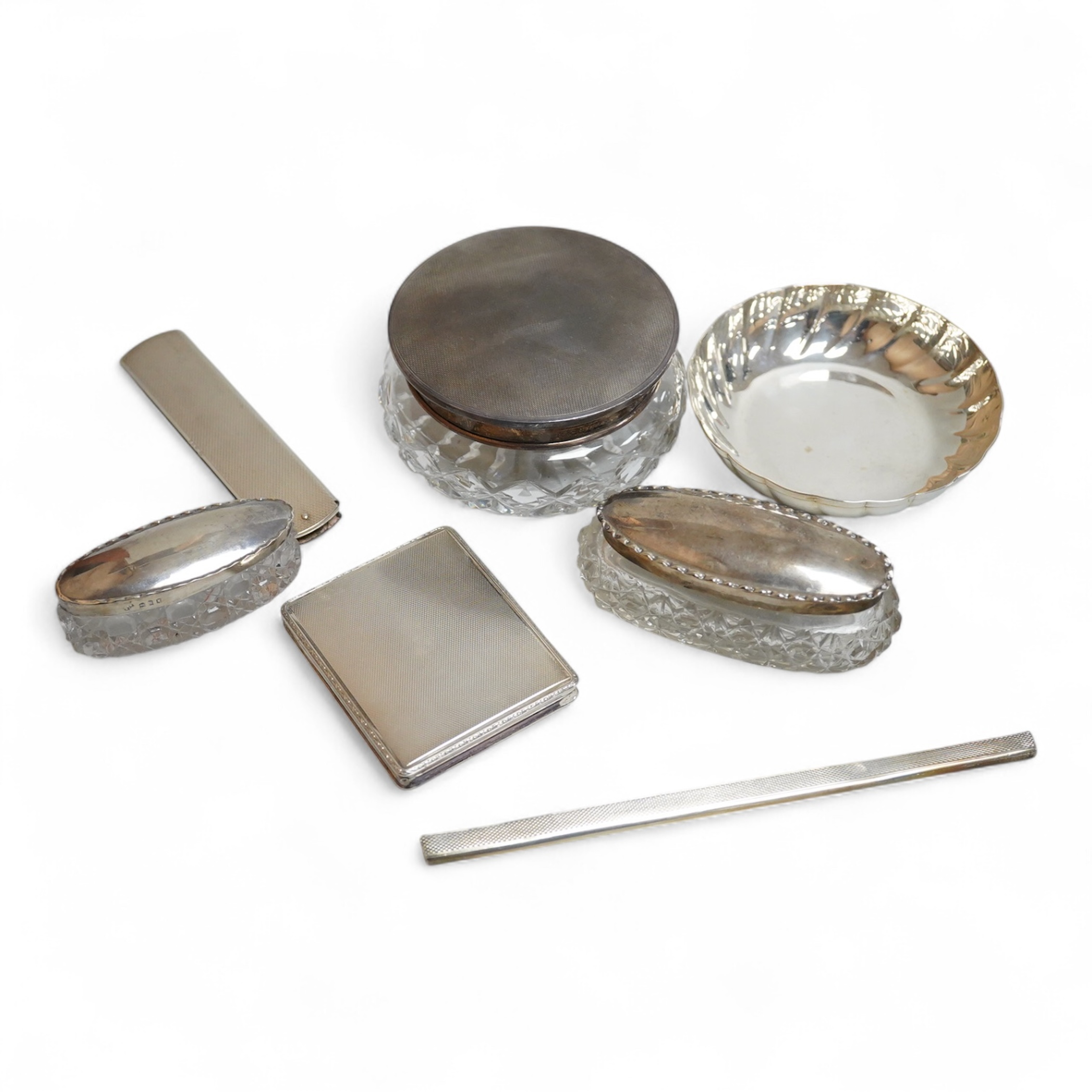 An 835 standard engine turned white metal powder compact, 72mm, three silver mounted glass toilet jars, two silver mounts and an Italian 800 standard small dish.